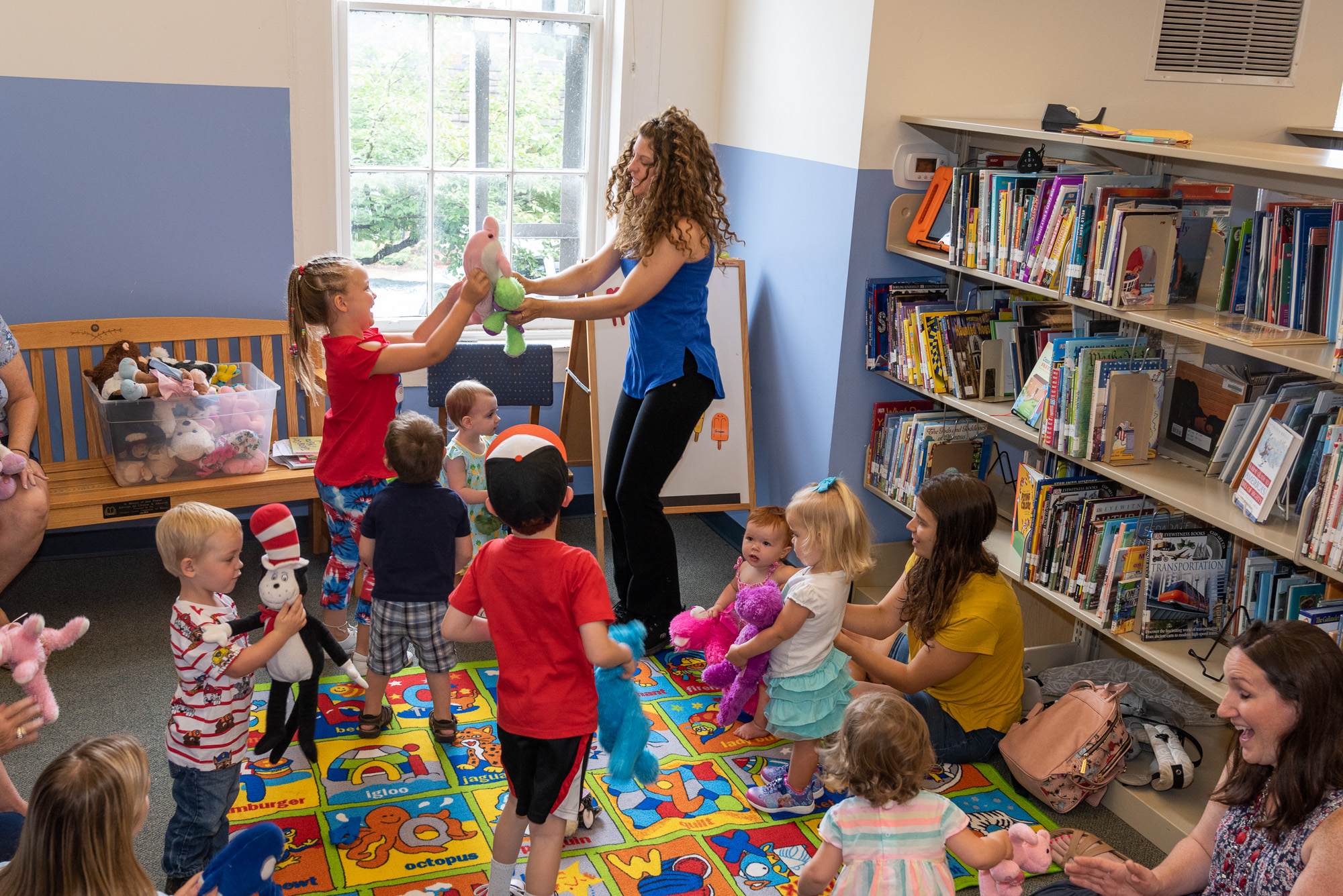 Color photo of Story Time at the Washington Street Library. Photo shows librarian leading a dance session with stuffed animals during story time .
